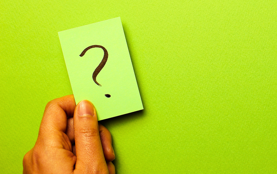 man's hand with question mark over a green background dealing with the uncertain